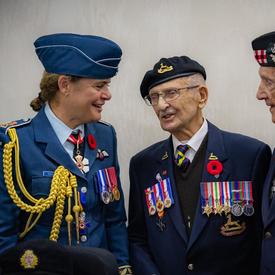 Governor General Julie Payette, wearing the Royal Canadian Air Force uniform, is smiling, talking with veterans.
