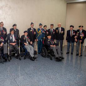 Governor General Julie Payette, wearing the Royal Canadian Air Force uniform, is posing for a photo with veterans.