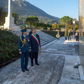 Governor General Julie Payette, wearing the Royal Canadian Air Force uniform, is standing in front of a monument with the mayor of the city, in Cassino.