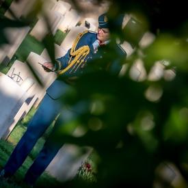 Governor General Julie Payette, wearing the Royal Canadian Air Force uniform, is seen from a distance, in the shadow of a tree, visiting the Cassino War Cemetery.