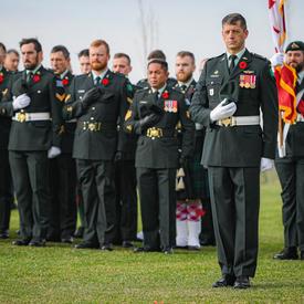 Canadian Armed Forces members stand with their hands over their hearts. 