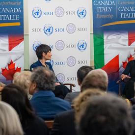 The Governor General is sitting on stage beside Italian astronaut Samantha Cristoforetti. 
