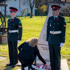 The Governor General lays a scarf on a monument at the Villanova Canadian War Cemetery.