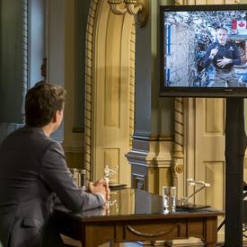Canadian Space Agency astronaut David Saint-Jacques is on a television screen talking from the International Space Station. 