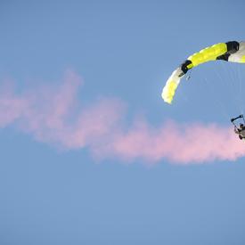 Un membre des Forces armées canadiennes descend du ciel en parachute. 