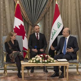 Governor General Julie Payette and His Excellency Barham Salih, President of Iraq are speaking to each other. An interpreter is sitting between them. The flags of Canada and Irak are in the background.