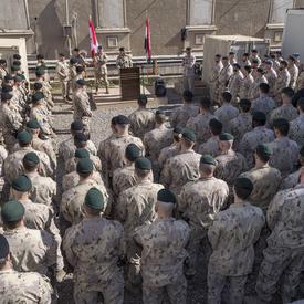 Des dizaines de membres des Forces armées canadiennes écoutent la Gouverneure générale Julie Payette prendre la parole à une tribune. 