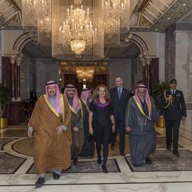 La gouverneure générale Julie Payette marche dans la palais Bayan entourée d'hommes Koweïtiens.