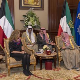 La gouverneure générale Julie Payette est assise avec trois hommes koweïtiens. Des drapeaux colorés sont derrière eux.