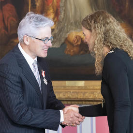 The Governor General shakes the hand of Gaston Déry.  They are facing each other and exchanging a few words. 