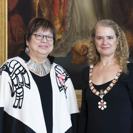 The Governor General stands next to Judith Sayers.  Both are wearing their Order of Canada insignia. 