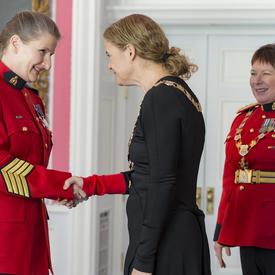 Diane L. Cockle shakes the Governor Generals hand.  Standing behind them to the right is RCMP Commissioner Brenda Lucki.  All three are wearing their insignia. 