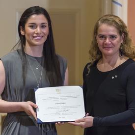 Ciera Disipio is holding her certificate and posing for a photo beside the Governor General. 