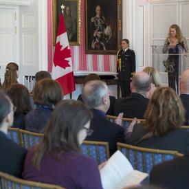 The Governor General is speaking from a podium. The audience is listening to her. 