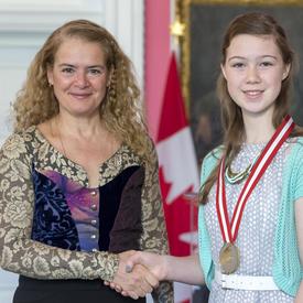 The Governor General is shaking Kaira Picard’s hand. 