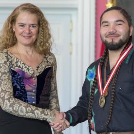 The Governor General is shaking Tehatsistahawi Kennedy’s hand. 
