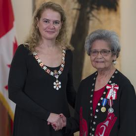 Marjorie White stands next to the Governor General.  Both smile at the camera.  They are wearing their Order of Canada insignia.