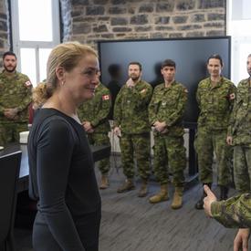 La gouverneure générale Julie Payette écoute une femme en uniforme de combat. A côté de la femme, d'autres personnes portant l'uniforme sont alignées, attendant aussi de lui parler.