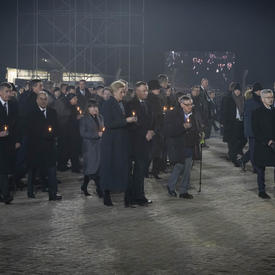 Des survivants et des leaders mondiaux marchent avec des bougies à la main. 