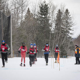 Athletes compete outdoors in a tight snowshoeing race.