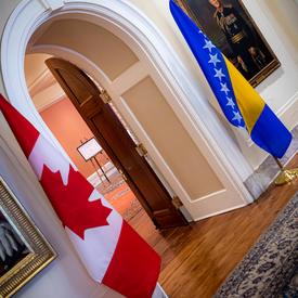 The Canadian and Bosnia and Herzegovina flags are on either side of a door. 