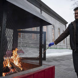 A photo of a man roasting a marshmallow on a fire at Rideau Hall. 