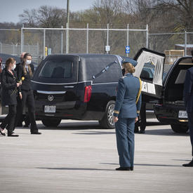 Les membres de la famille du décédé se dirigent vers le corbillard. La gouverneure générale et le premier ministre se tiennent près du corbillard.