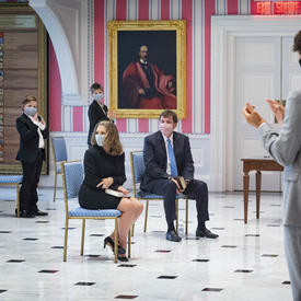 Un homme et une femme sont assis tandis qu'un petit nombre de spectateurs applaudissent.