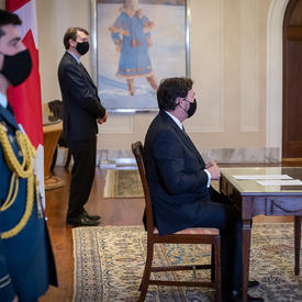 The Administrator sitting at table with the Secretary to his left and an aide-de-camp to his right.