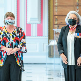 Une femme fraîchement décorée d’une médaille se tient près de la gouverneure générale Mary May Simon. Toutes deux portent un masque.