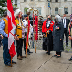 La gouverneure générale échange avec d’autres personnes rassemblées devant le monument.