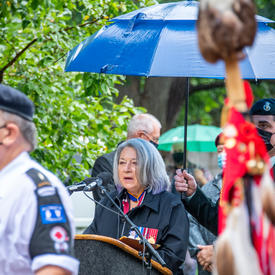 La gouverneure générale prononce son discours. Elle est à l’extérieur. Il pleut.