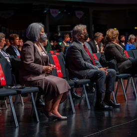Their Excellencies are seated in the front row at the Canada Pavilion for the opening of the Frankfurt Book Fair. There is an audience seated behind them. 