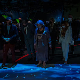  Their Excellencies are standing in a small group admiring the light show at the Canada Pavilion. 