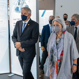 The Governor General and Mr. Whit Grant Fraser and a man in a dark suit are walking together inside. 