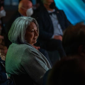 The Governor General is seated at the Canada Pavilion. The lighting is dark. She is smiling.