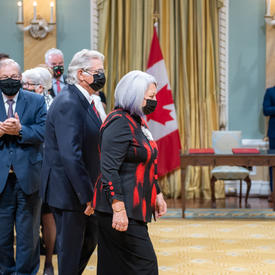 Their Excellencies are shown entering the Tent Room at Rideau Hall. The audience is shown standing and applauding them.