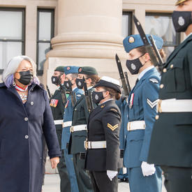 La gouverneure générale passe devant une rangée d'officiers en uniforme alors qu'elle entre au Sénat.