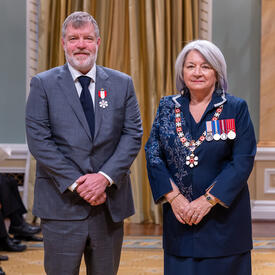 Robert Anthony Clark is standing next to the Governor General.