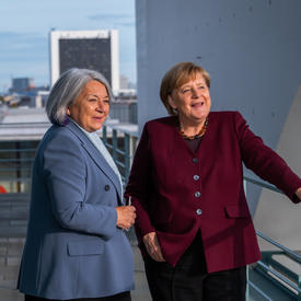 Governor General Mary Simon and Her Excellency Angela Merkel, Chancellor of Germany, are standing on a balcony. The Bundestag is visible behind them.
