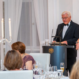 A man standing at a podium speaking to the crowd at the State dinner.