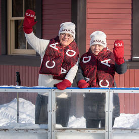 Their Excellencies waving to the camera, wearing official Olympic mittens, scarves and toques.