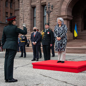 Le gouverneur général Simon se tient sur un podium rouge à l’extérieur de Queen’s Park.