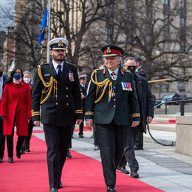 Governor General Simon is walking alongside a man in a military uniform.