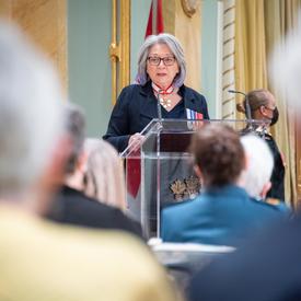 Photo de dos des récipiendaires alors que la gouverneure générale parle depuis un podium.