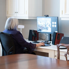 The Governor General is sitting at a computer. She is participating in a virtual event.