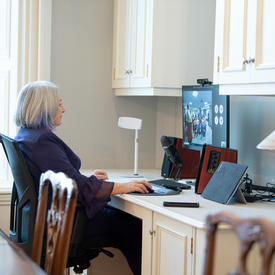 The Governor General is sitting at a computer. She is participating in a virtual event.
