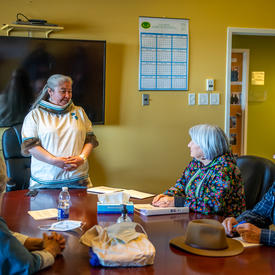 La gouverneure générale est assise à une grande table de conférence. La mairesse de Kuujjuaq est debout.  