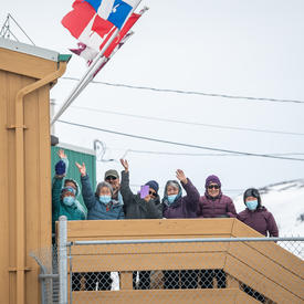 Une foule de personnes salue à l'extérieur de l'aéroport.