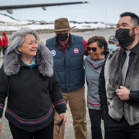 The Governor General is walking next to the Mayor of Kangiqsualujjuaq outside the airport.